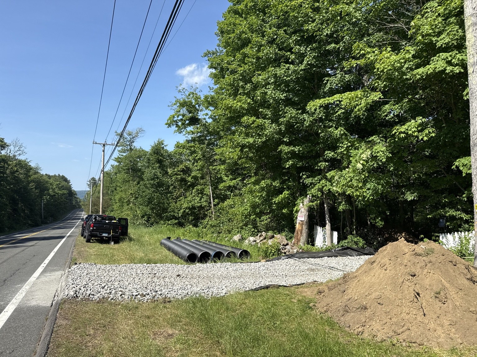 After image of driveway entrance with stone and culvert pipes staged nearby